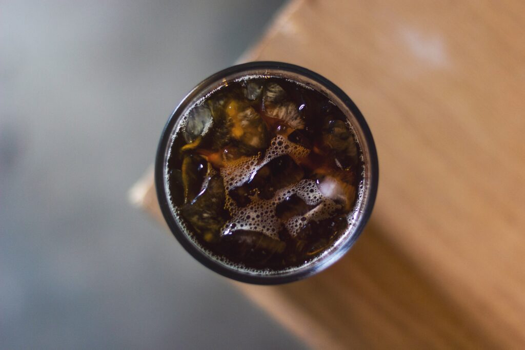 Top view of a glass filled with iced coffee, placed on a wooden surface.