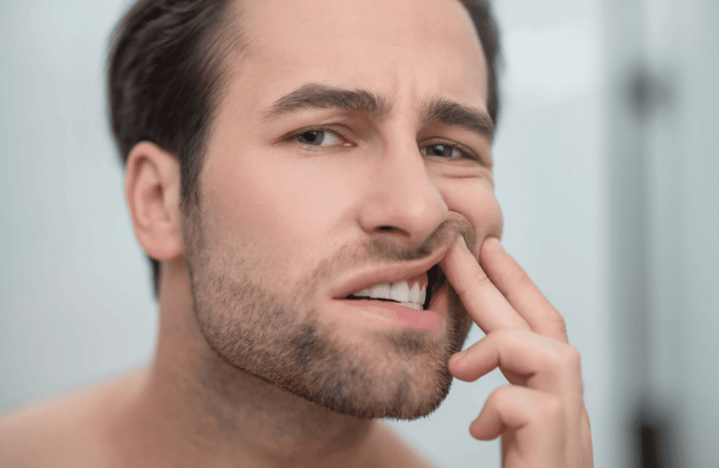 man inspecting his gums and teeth