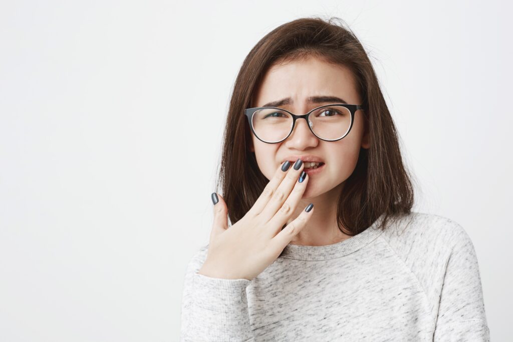 Young-woman-experiencing-oral-discomfort-hand-covering-mouth-indicative-of-symptoms-like-dry-mouth