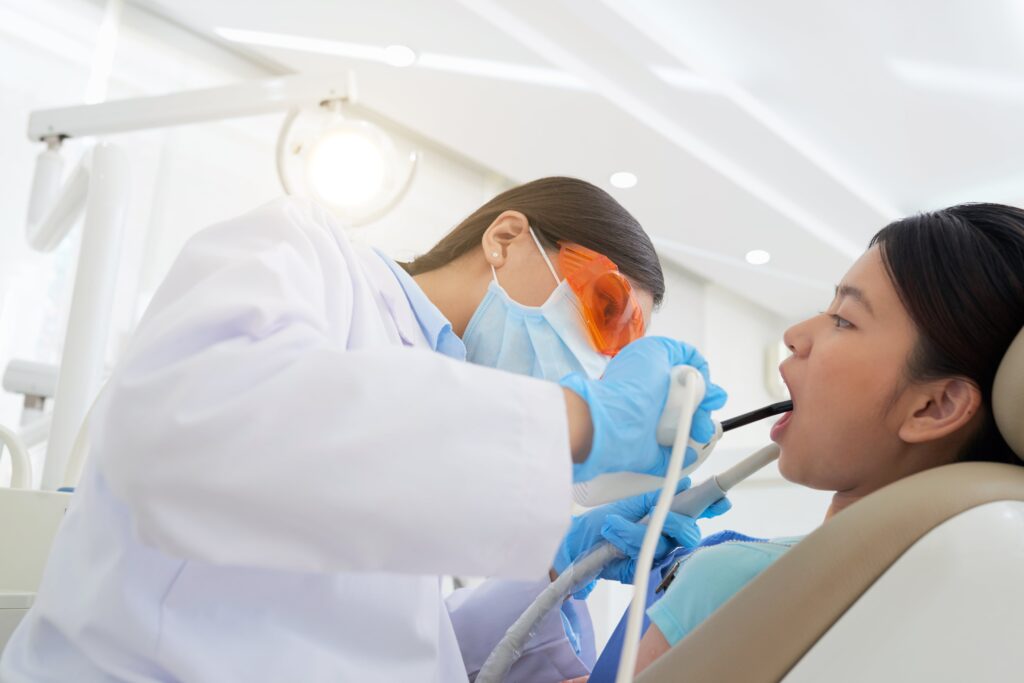 Female dentist performing a dental cleaning on a young patient in a clinic, showcasing modern dental care.